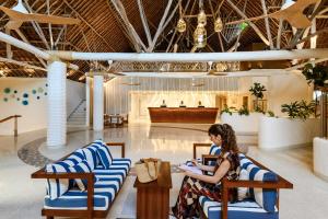 a woman sitting in chairs in a lobby at Diamonds Leisure Beach & Golf Resort in Diani Beach