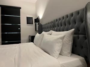 a white bed with a black headboard and white pillows at Apollonio Suites in Korinthos