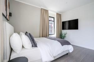 a bedroom with a white bed with pillows and a tv at Oak Suite · District 4 in Zurich