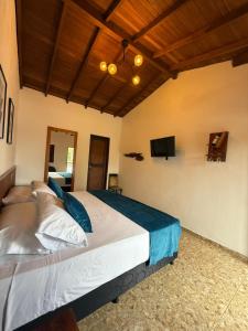 a bedroom with a large bed with a tv on the wall at Hotel Dulce Campestre in Jardin