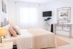 a white bedroom with a bed and a television at Avenue Apartment - Family-friendly T2 - Estacionamento Privado in Quarteira