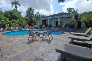 a patio with a table and chairs next to a pool at Spicy Hill Villa in Port Antonio