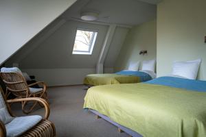 a attic room with two beds and a chair at Landhuis Hotel Restaurant Rikus in Eext