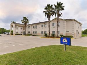 a sign in front of a building with palm trees at Americas Best Value Inn Somerville Texas in Somerville