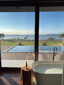 a bathroom with a tub and a view of a swimming pool at Lagoon Suites e Gastronomia in Laguna +34 photos