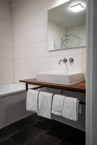 a bathroom with a sink and a tub and towels at Landhuis Hotel Restaurant Rikus in Eext