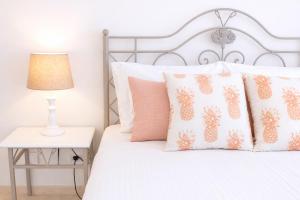 a bedroom with a white bed with pineapple pillows at Avenue Apartment - Family-friendly T2 - Estacionamento Privado in Quarteira +18 photos
