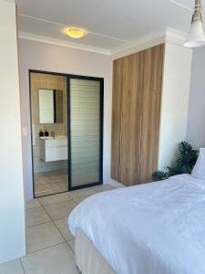 a bedroom with a white bed and a bathroom at Lagoon escape Apartment in Pretoria