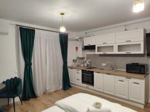 a kitchen with white cabinets and green curtains at Vivien Residence 2 in Baia Mare
