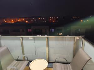 two chairs and a table on a balcony at night at Vivien Residence 2 in Baia Mare