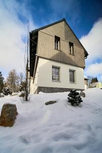 a large house in the snow with snow at Apartmány U Kovárny in Horní Blatná