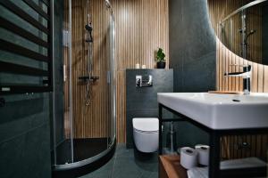a bathroom with a sink and a shower and a toilet at Calma - apartamenty z ogrodem blisko Energylandii in Zator +120 photos