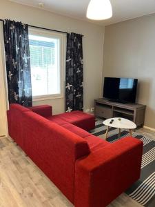 a living room with a red couch and a television at Apartment Annalantie in Pyhäjoki