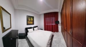 a bedroom with a white bed and a red curtain at Perle studio lac 2 tunisia mall in Tunis