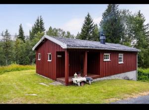 a red barn with a bench in a yard at Fjellhytte Rauland in Austbø