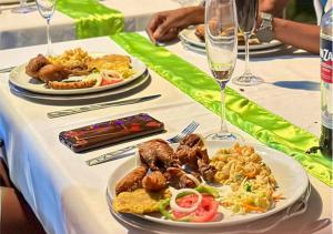 a table with plates of food and glasses of wine at Master Universel Hotel Bar Restaurant in Cap-Haïtien