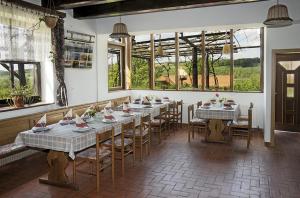 uma sala de jantar com mesas, cadeiras e janelas em Tourist Farm Ferencovi em Cankova