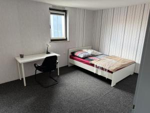 a bedroom with a bed and a desk and a chair at Zimmervermietung Kimberly in Bischbrunn