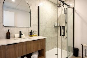 a bathroom with a shower with a sink and a mirror at La Capitainerie du Lac-Mégantic in Lac-Mégantic +173 photos