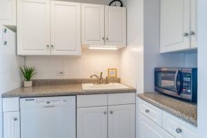 a kitchen with white cabinets and a sink and a microwave at Hale Ono Loa 204 in Lahaina