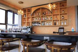 a bar with wooden stools and bottles of alcohol at Abrish Hotel and Apartment in Kampala