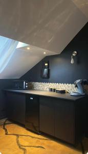 a kitchen with black cabinets and a white counter top at Love Room in Canteleu