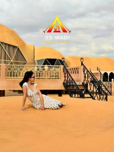 a woman sitting on the ground in front of a building at X5 wadi Rum Luxury in Wadi Rum