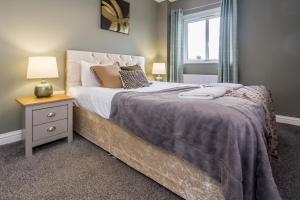 a bedroom with a bed with a nightstand and a window at 61 Deneside in Lanchester