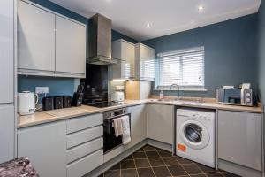 a kitchen with white cabinets and a washer and dryer at 61 Deneside in Lanchester