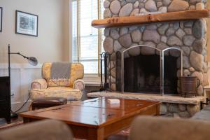 a living room with a stone fireplace and a chair at Pine Trace Escape in Glen Arbor in Glen Arbor +47 photos