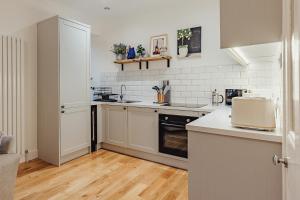 a kitchen with white appliances and wooden floors at The Wee Harbour Home in Anstruther