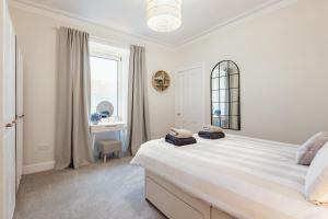 a white bedroom with a large bed and a window at The Wee Harbour Home in Anstruther