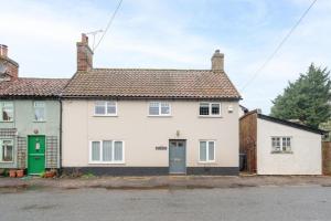 a white house with a green door on a street at Hollyhocks, Tunstall in Tunstall