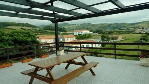 a wooden picnic table on a balcony with a view at Alice's House in Horta