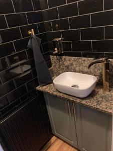a bathroom with a sink and a black tiled wall at LILI Deluxe Apartman in Tapolca +9 photos