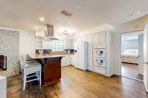 a kitchen with white cabinets and a sink and refrigerator at Poolside Bliss! Christian Pass Family Home w/ Yard in Long Beach +18 photos
