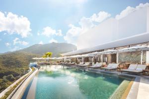 a resort pool with chairs and a mountain in the background at Garza Blanca Sanctuary Puerto Vallarta in Puerto Vallarta