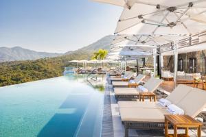 a pool at a resort with white lounge chairs at Garza Blanca Sanctuary Puerto Vallarta in Puerto Vallarta