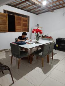 a woman sitting at a table in a kitchen at Recanto Família lima e Silva in Garanhuns