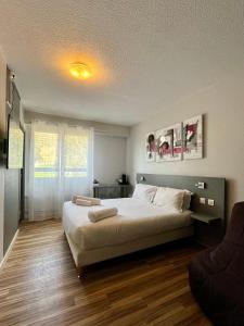 a bedroom with a large bed and a window at Logis Hôtel de la Bruyere in Pouzauges