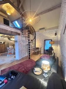 a living room with a couch and a spiral staircase at L'écurie du vigneron in Châtillon-sur-Cher +8 photos