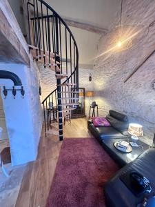 a living room with a couch and a spiral staircase at L'écurie du vigneron in Châtillon-sur-Cher