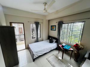 a bedroom with a bed and two windows at Gulshan Guest House in Dhaka