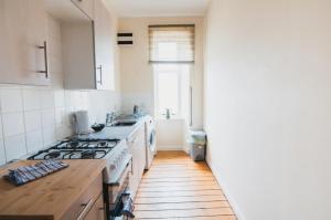 a kitchen with white appliances and a wooden floor at Causeyside apartment in Paisley