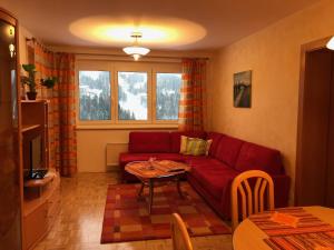 a living room with a red couch and a table at Sonnenalpe ckpk in Hermagor