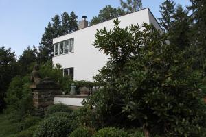 a white house with a statue in front of it at Villa Čisovice - Functionalist Retreat near Prague in Čisovice