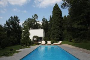 a swimming pool in a yard with two chairs and a house at Villa Čisovice - Functionalist Retreat near Prague in Čisovice