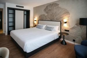 a bedroom with a large white bed and a wall at URH Ciutat de Mataró in Mataró
