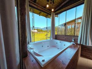 a large bath tub in a room with windows at Chalés Aconchego dos Canyons in Praia Grande +54 photos