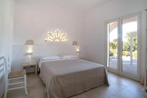 a white bedroom with a bed and a sliding glass door at Podere Santa Chiara in Otranto +88 photos